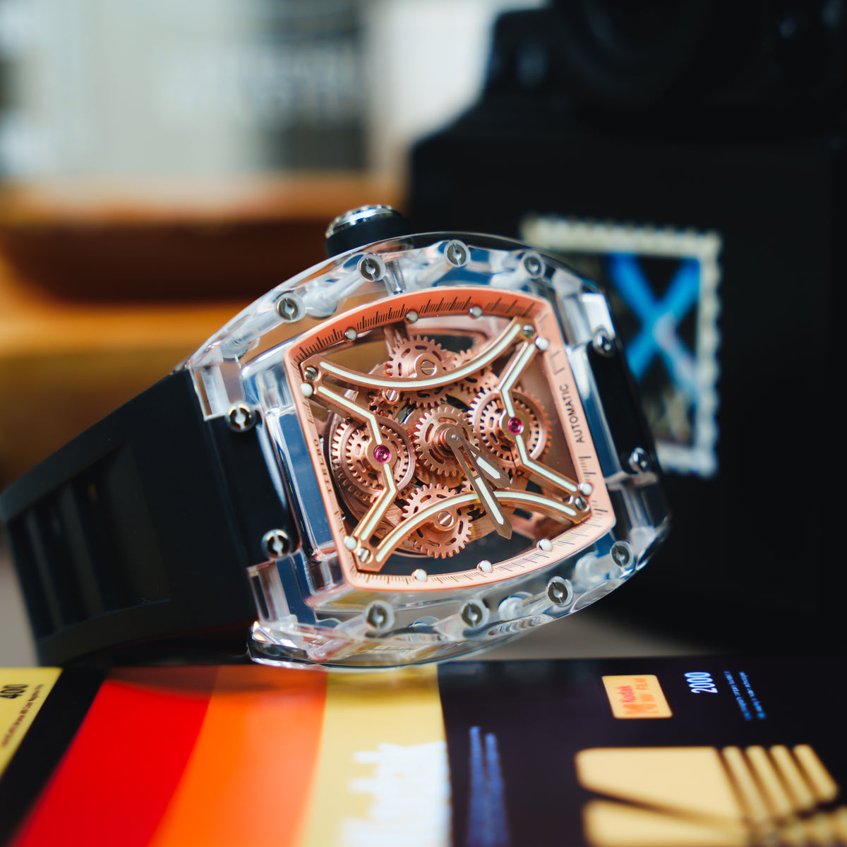 T832M Nightwalker with a rose-gold-tone openwork dial and black strap, displayed beside a camera and film packaging; original manufacturer photograph